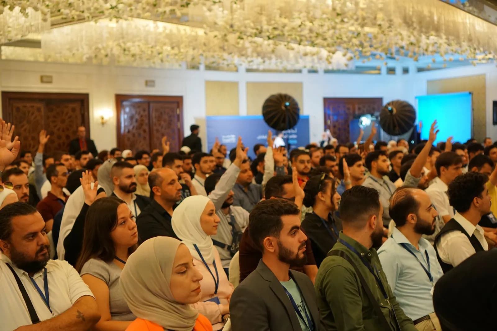 A full room of attendees raising their hands during a session